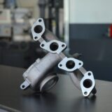 Metallischer Abgaskrümmer mit mehreren Flanschöffnungen auf einer Werkbank